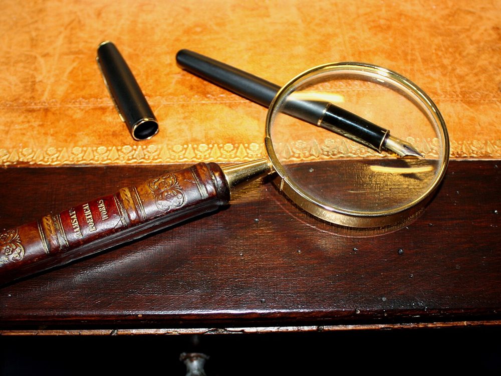 A magnifying glass and pen on a desk